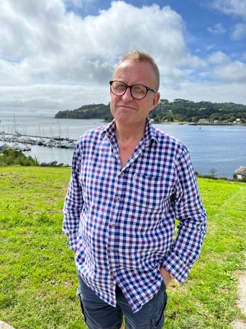 Andy in blue chequered shirt stood by River Tamar. Sunny day.