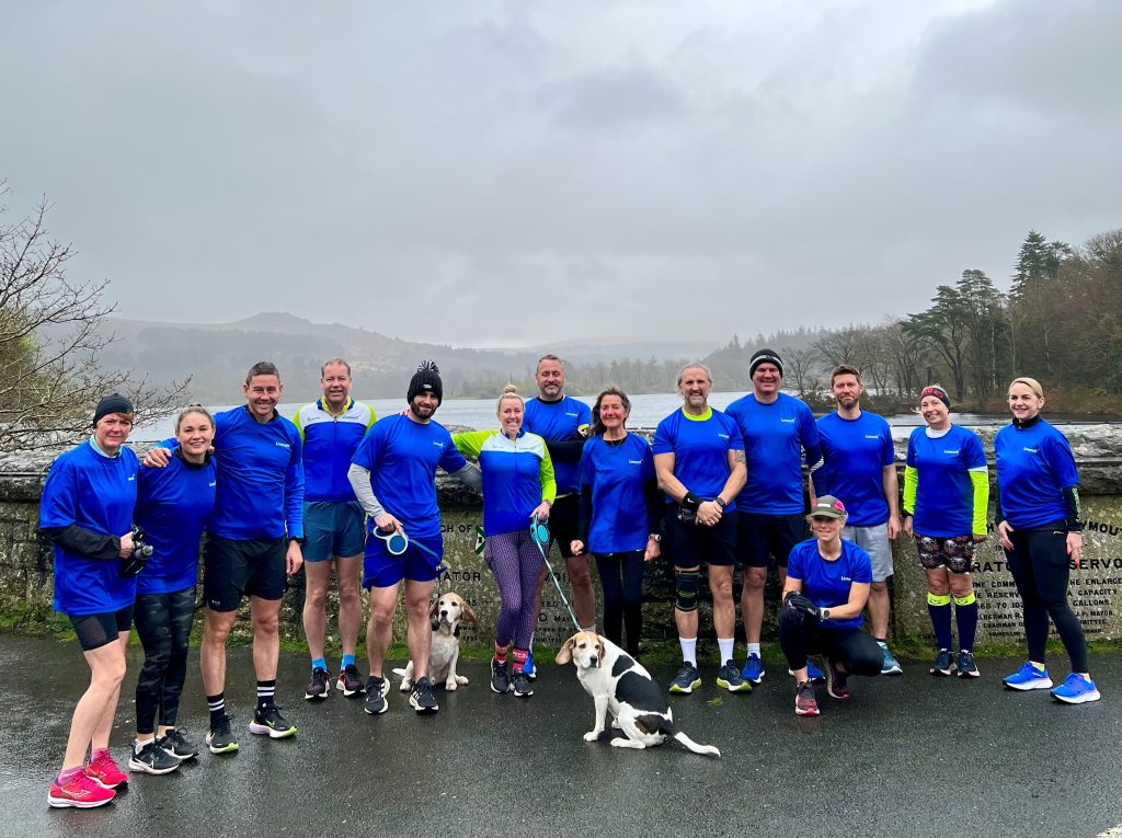Team of runners wearing blue Livewell Southwest t-shirts by Burrator reservoir