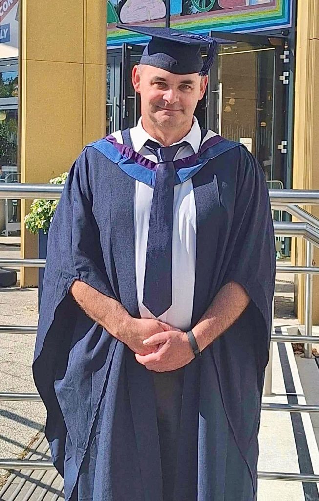 Mark in graduation gown and mortarboard