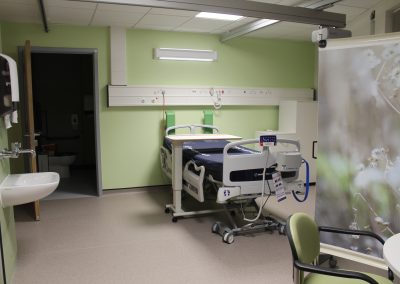 Bed in hospital en-suite room with a table and chairs