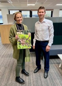Woman holding picture of a deer stood next to a man in office