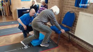 Man helping woman with an exercise to get up off the floor