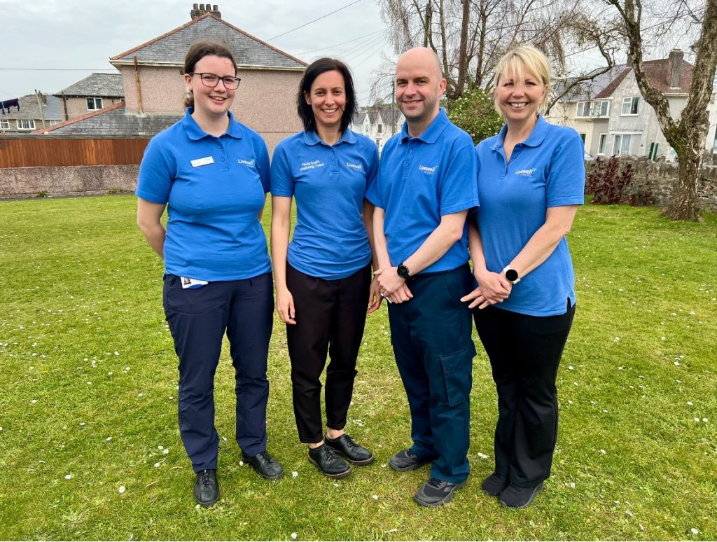 Three women and one man in blue t-shirts stood in garden