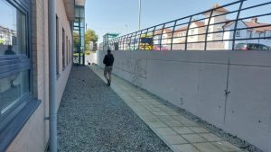 Empty white concrete wall with man walking beside it