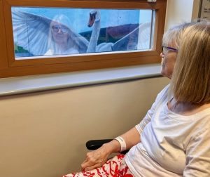 Woman in chair looking out at the artwork through ward window