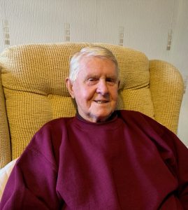 Man with grey hair sat in arm chair