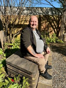Man sat on bench in garden