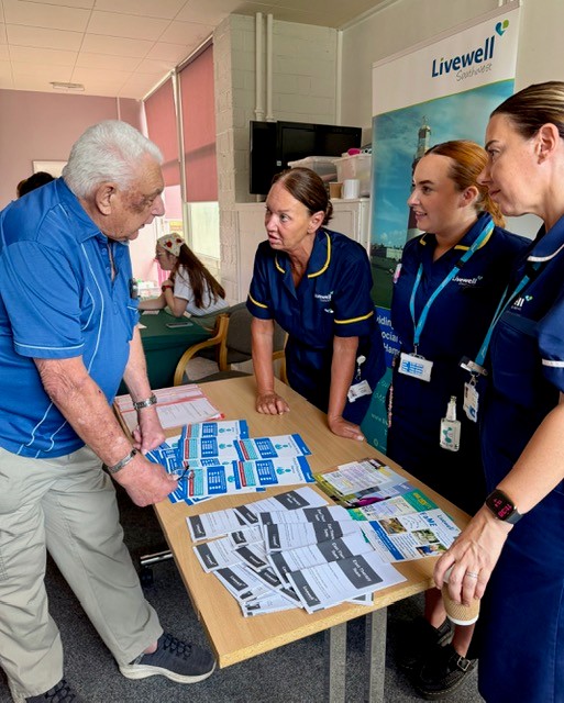 Community nursing team Three women in blue nurses' uniform talking to an older man