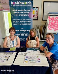 Three women sat behind an information desk