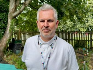 Man with grey hair, wearing white t-shirt