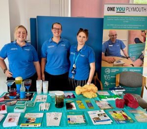 Three women in blue t-shirts behind information stand