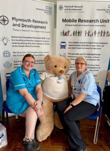 Two women in medical uniform aside a life size teddy bear