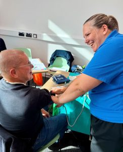 Woman in blue t-shirt taking a man's blood pressure